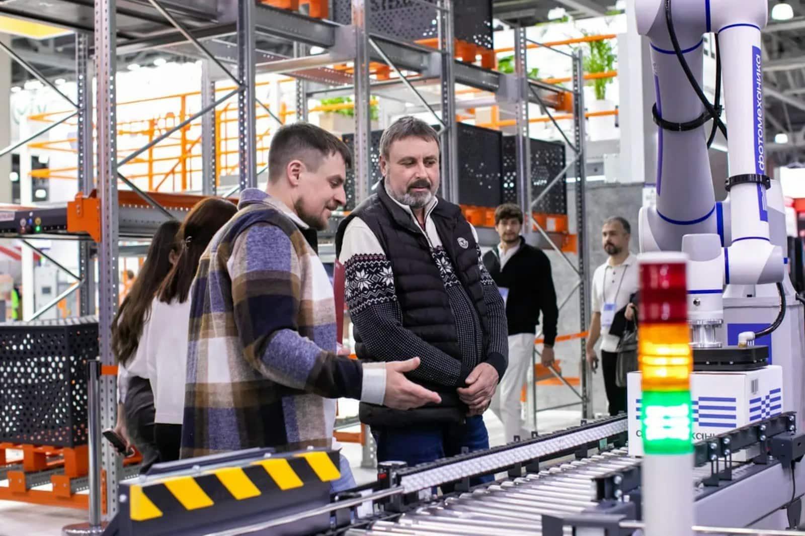 Integration team standing at a conveyor and robot cell discussing an installation on the floor.